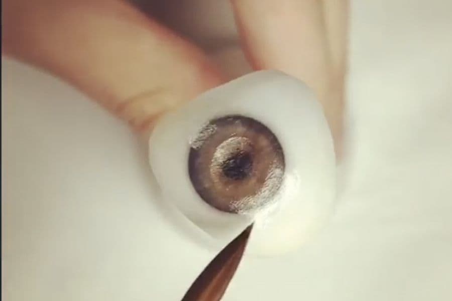 Pincel fino pintando el iris de una prótesis ocular