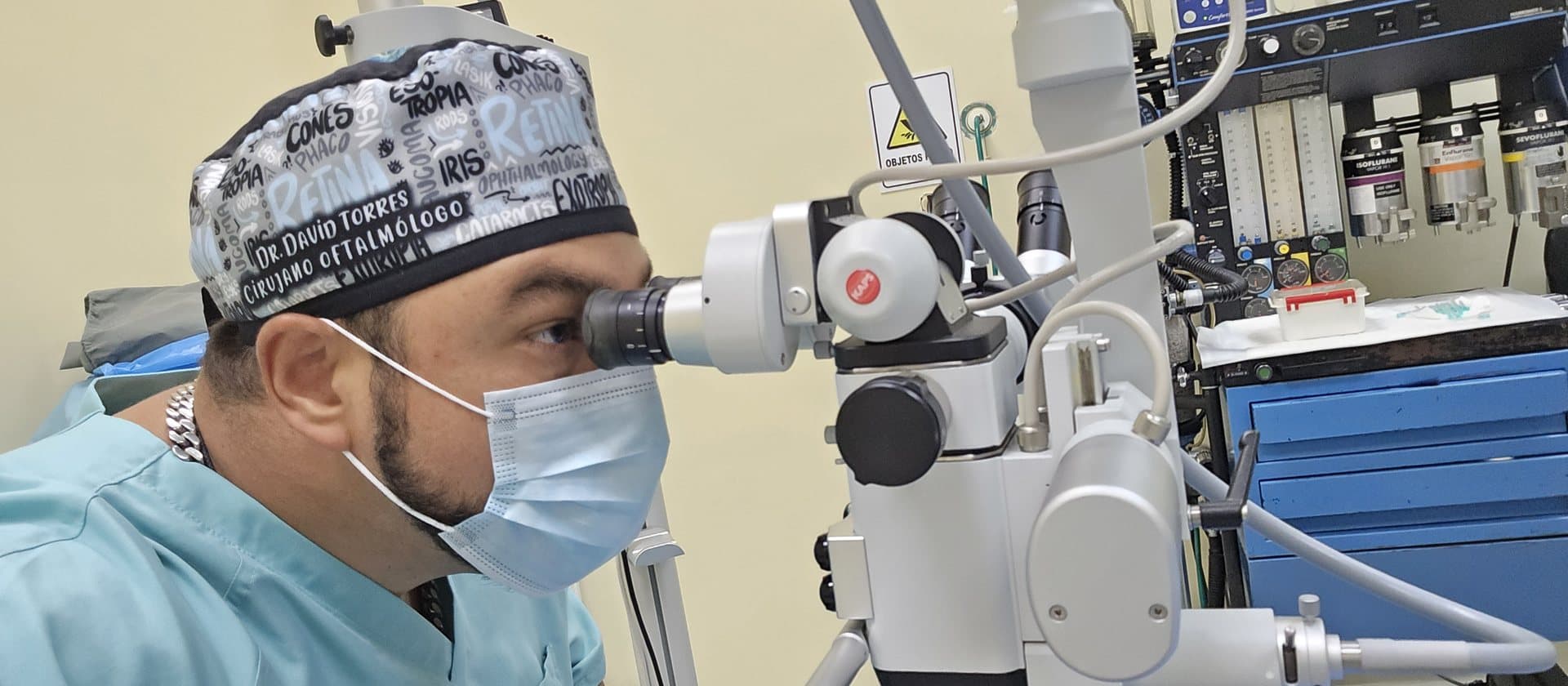 El Dr. Torres en el quirófano, mirando por el microscopio durante una cirugía ocular